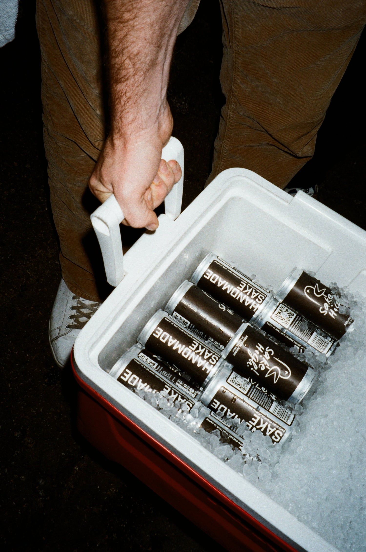 Person holding a cooler with Sake High! cans inside